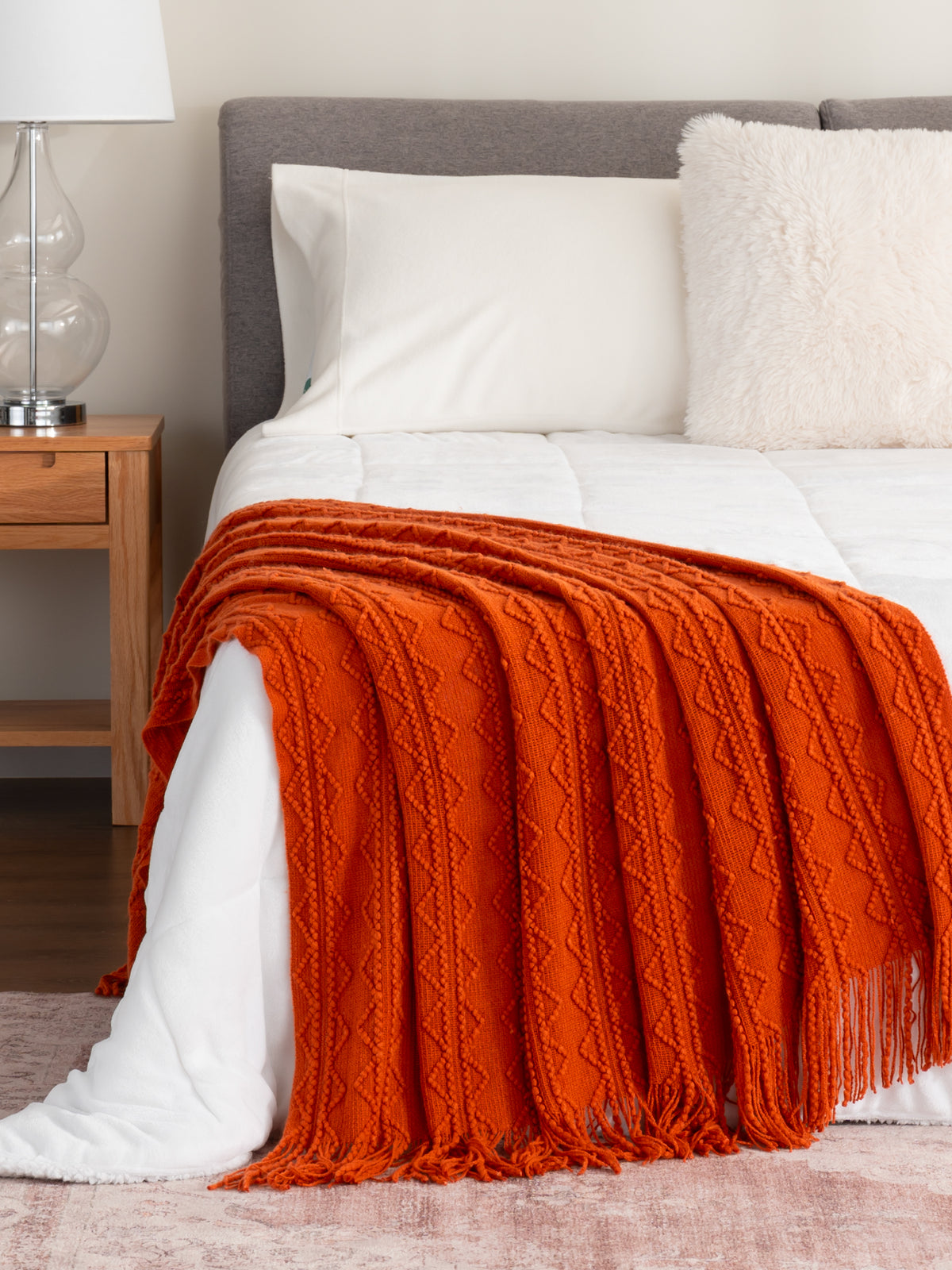 Throws collection image featuring our NEW Tassle Knit Throw in Pumpkin Puree draped over a white bed!