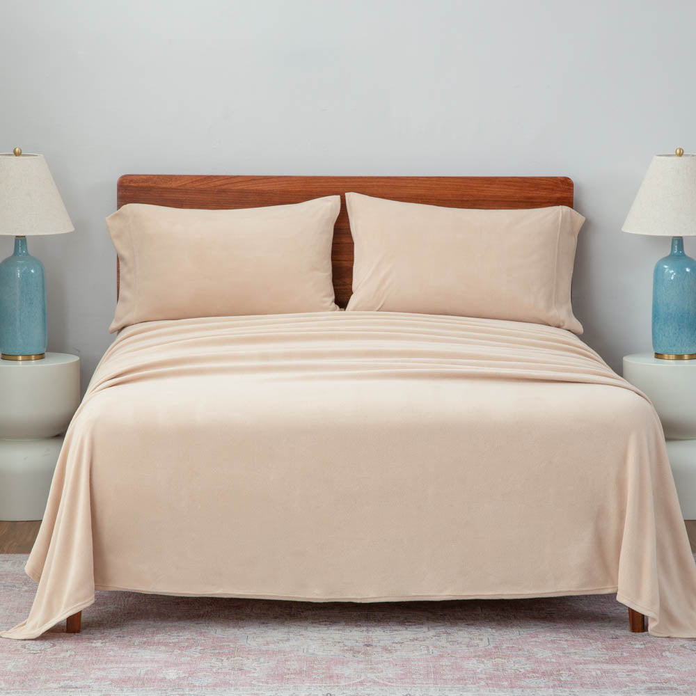 A neatly made bed with beige sheets and blue lamps on the nightstands.