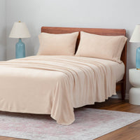 A neatly made bed with beige sheets and blue lamps on the nightstands.