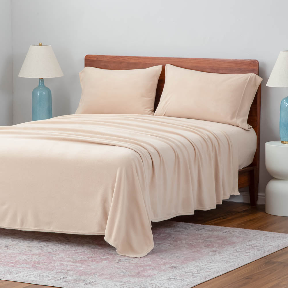 A neatly made bed with beige sheets and blue lamps on the nightstands.