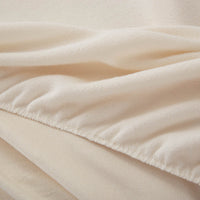 A close-up of a fitted ivory sheet, highlighting the fabric texture.