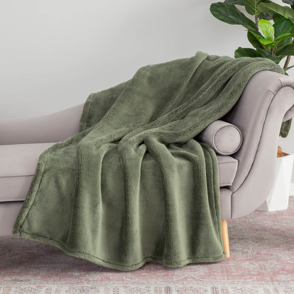 Green extra fluffy throw draped neatly over a grey chair.