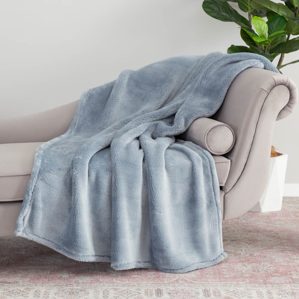 A blue extra-fluffy throw draped neatly over a grey chair.