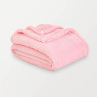 Pink extra fluffy throw folded neatly on a white surface.