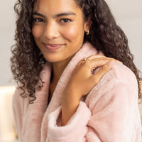 Woman wearing a pink robe with a neutral background