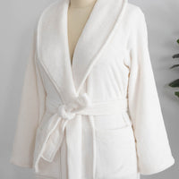 A white VelvetLoft Robe on a mannequin, displayed next to decorative items.