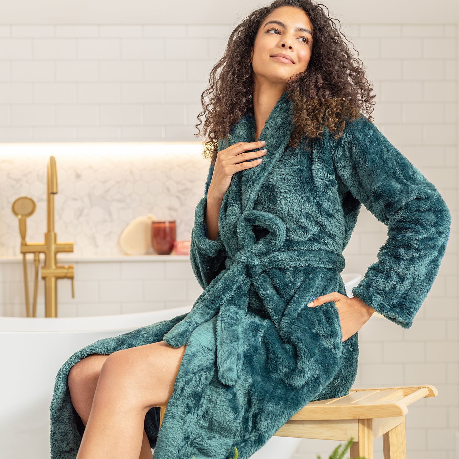 Woman wearing a teal robe in a bathroom setting