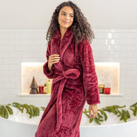 Woman wearing a red robe in a bathroom setting with decorative elements.