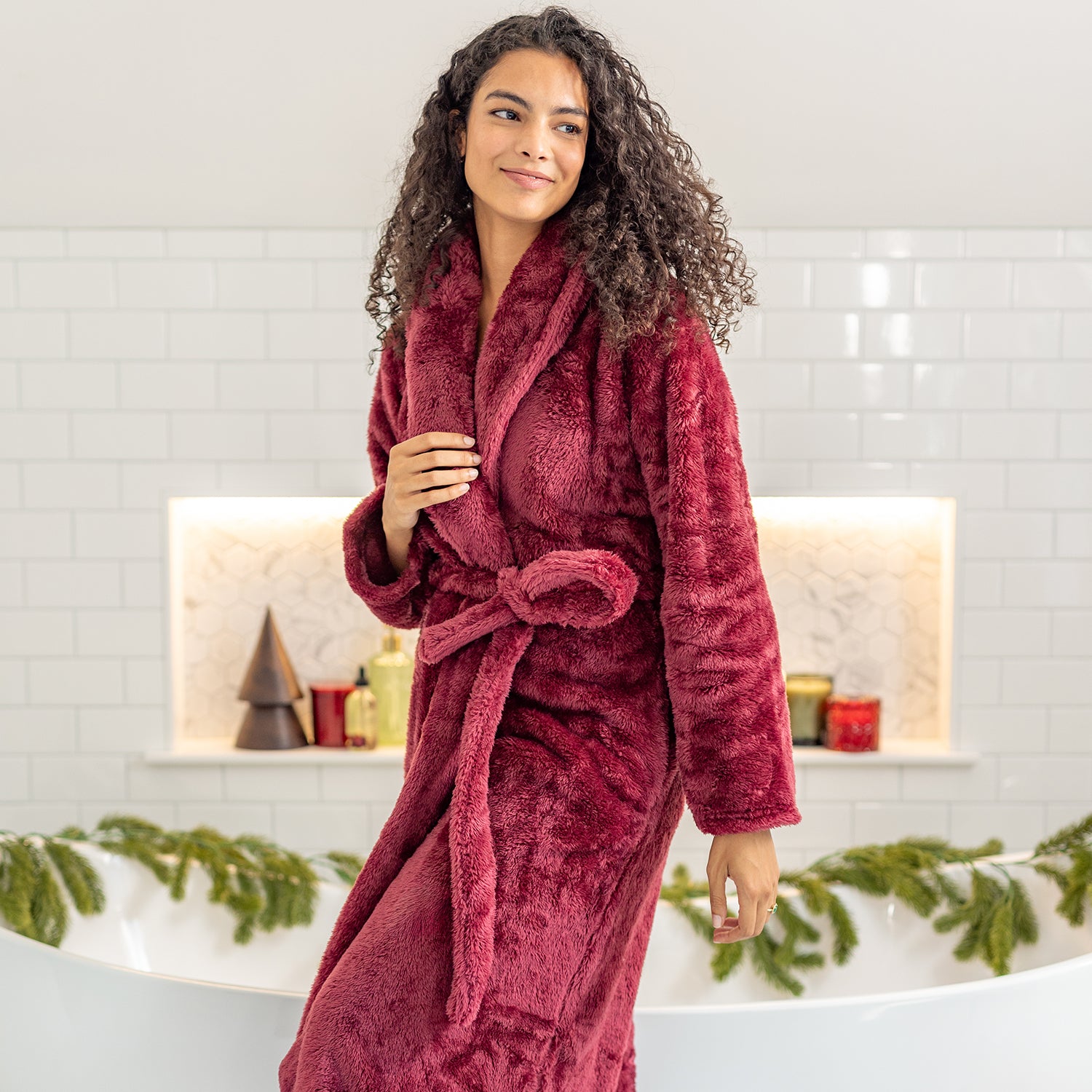 Woman wearing a red robe in a bathroom setting with decorative elements.