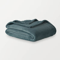 Dusk blue PrimaLush throw folded neatly on a white surface.