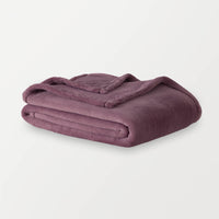 A purple PrimaLush throw folded neatly on a white surface.