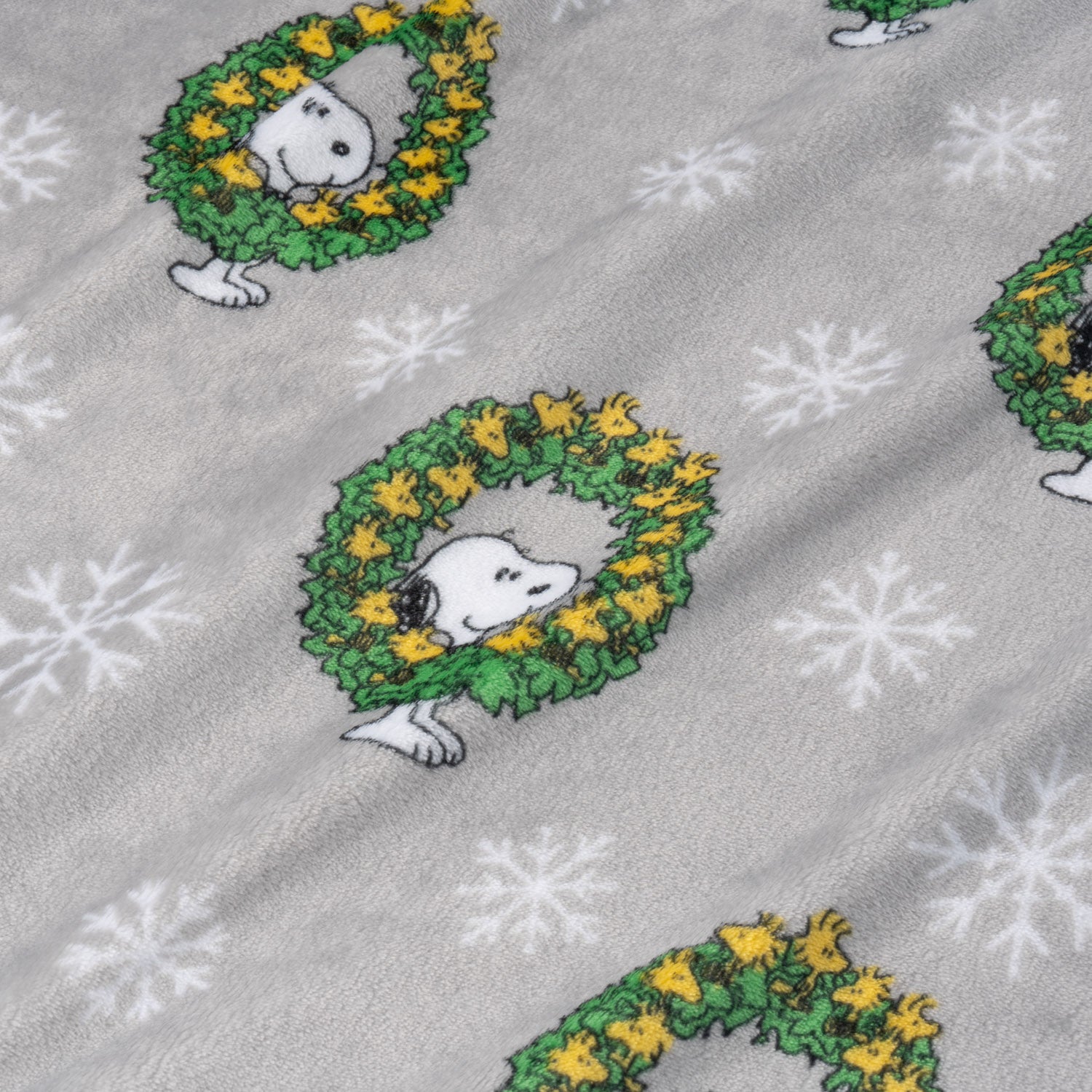 Fabric with Snoopy in wreaths and snowflakes on a gray background