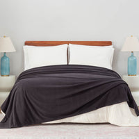 Black Polartec Softec Microfleece blanket spread neatly over a white bed with blue lamps on both sides.