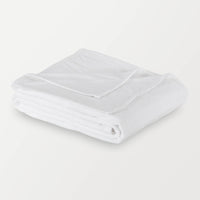Folded white Polartec blanket on a white background, highlighting its soft texture and design.