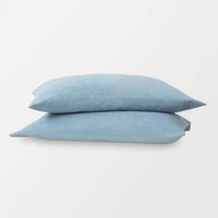 Blue pillowcases stacked ontop of eachother on a white surface.