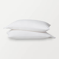 White pillowcases stacked ontop of eachother on a white surface.