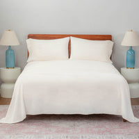 cream sheet set on a large bed with two lamps on either side.