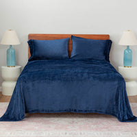 Dress Blue (Navy) plush sheet set on a large bed with two lamps on either side.