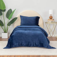 Dress blue (navy) sheet set styled with neutral decor accent, plant on one side and nightstand on other side.
