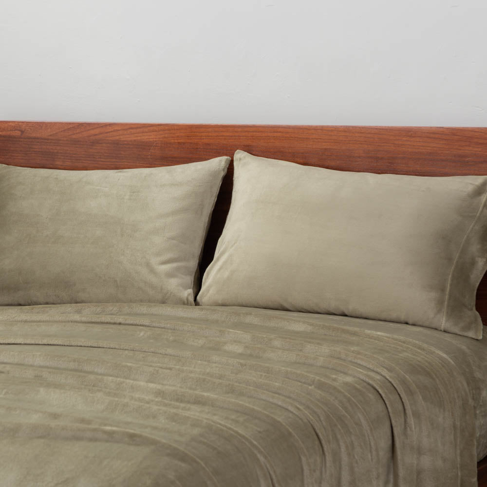 Dry Sage sheet set styled with two pillows on a bed.