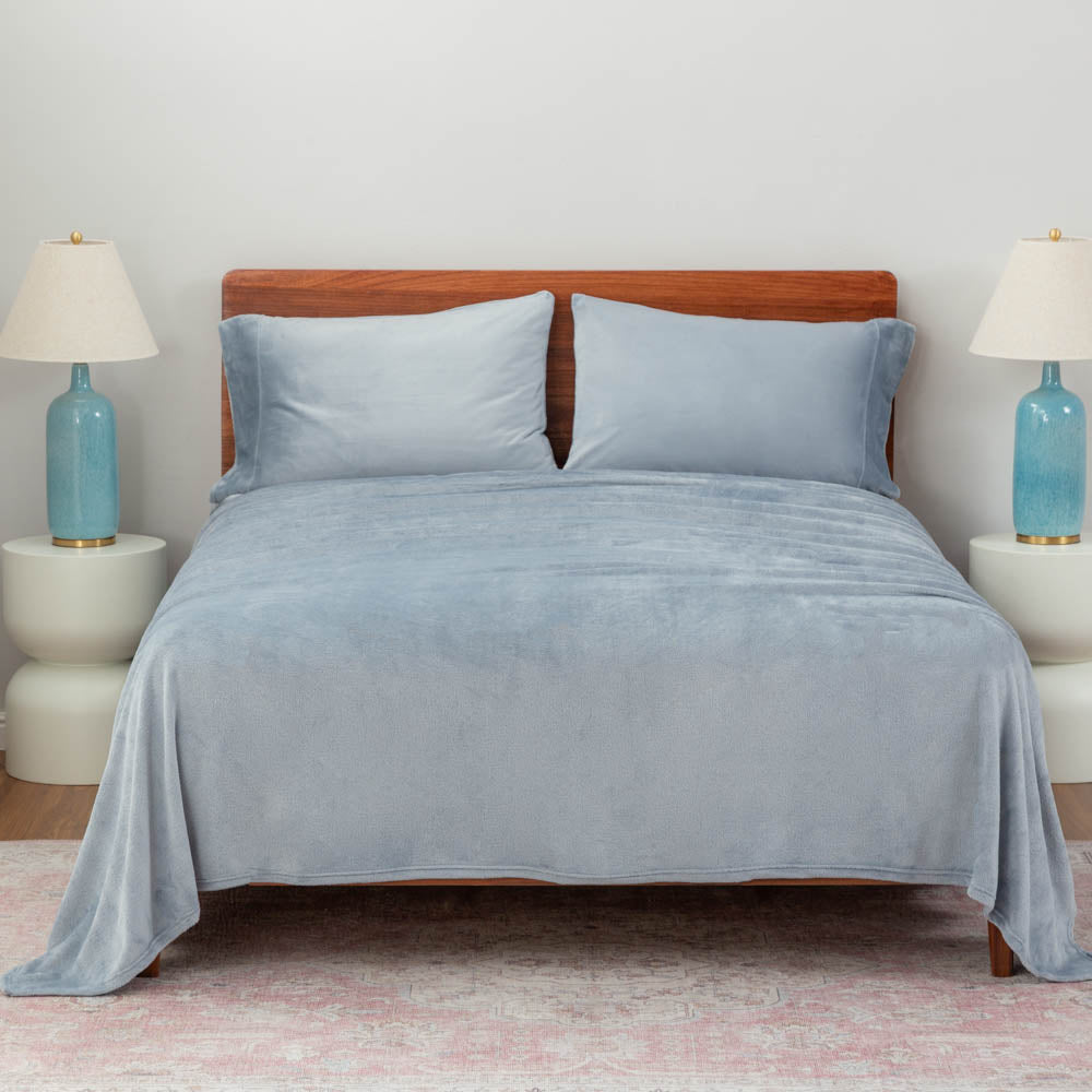 polar blue (light blue) sheet set on a large bed with two lamps on either side.