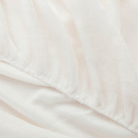 Close-up of White fitted sheet corner with plush texture.