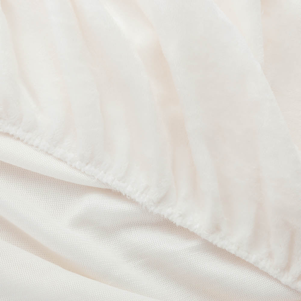 Close-up of White fitted sheet corner with plush texture.