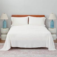 white plush sheet set on a large bed with two lamps on either side.