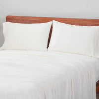 White heet set styled with two pillows on a bed.