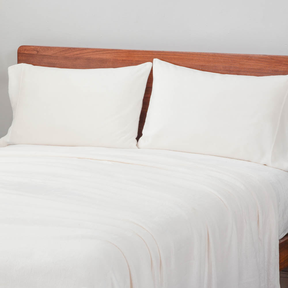 White heet set styled with two pillows on a bed.