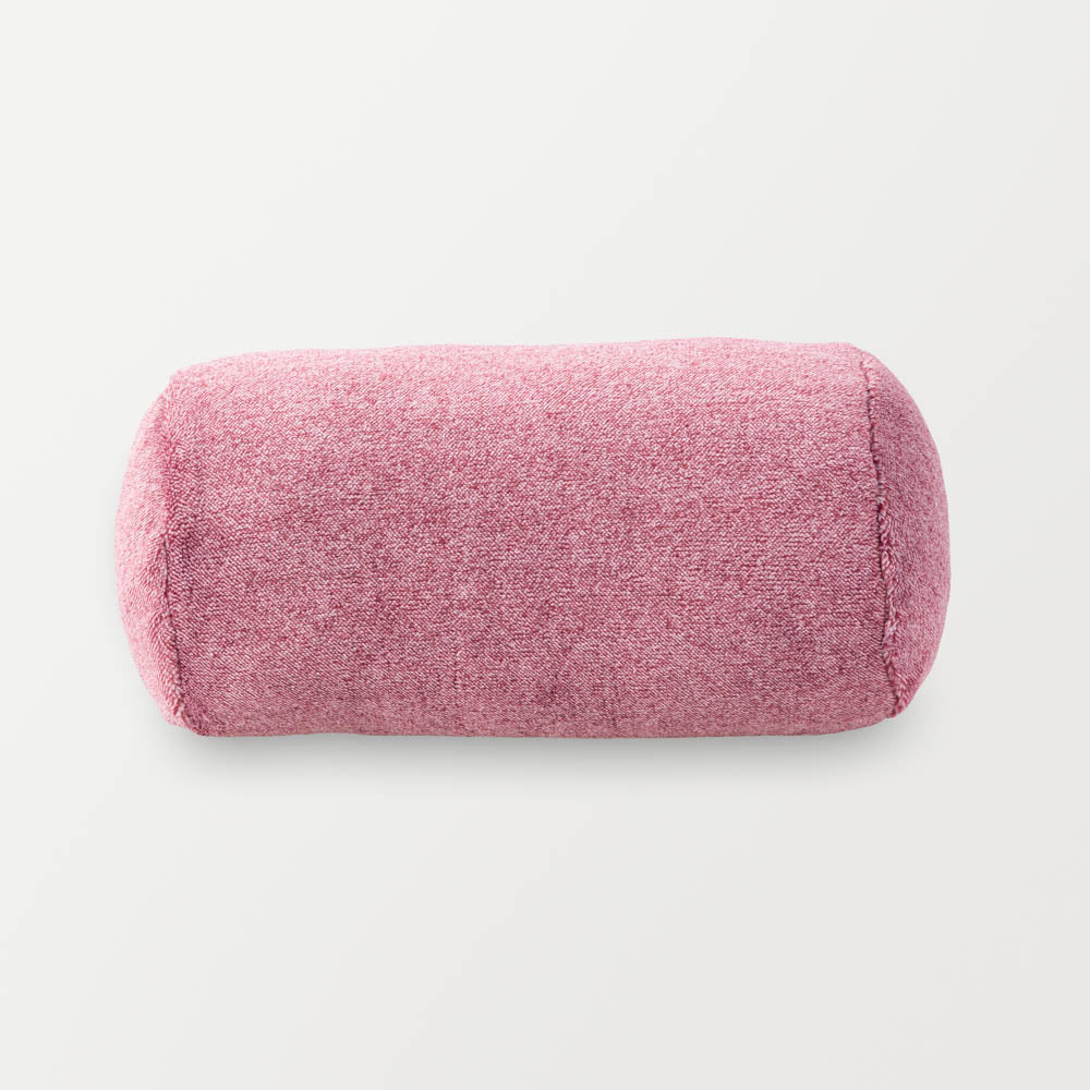 A pink EcoThread Neckroll Pillow sitting on a white surface.