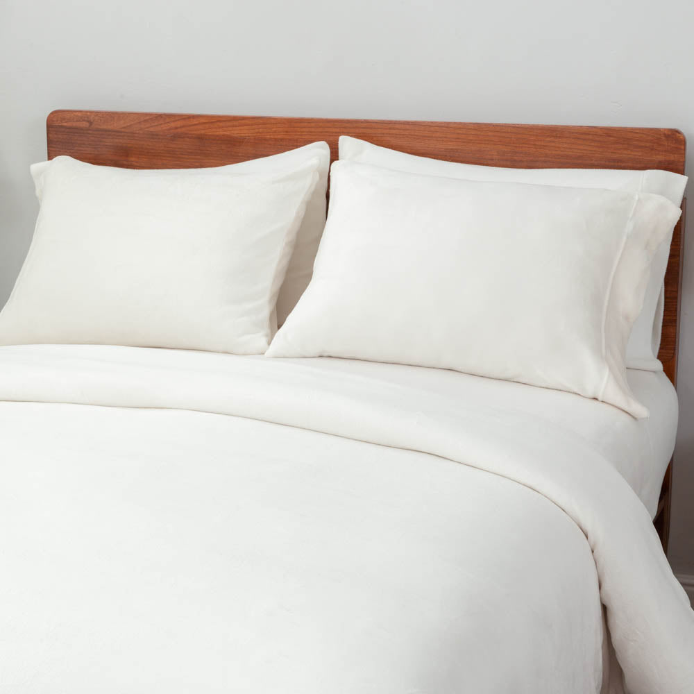A bed styled with the cream VelvetLoft® Plush Duvet Cover Set, featuring two large pillow shams and the duvet cover neatly draped."