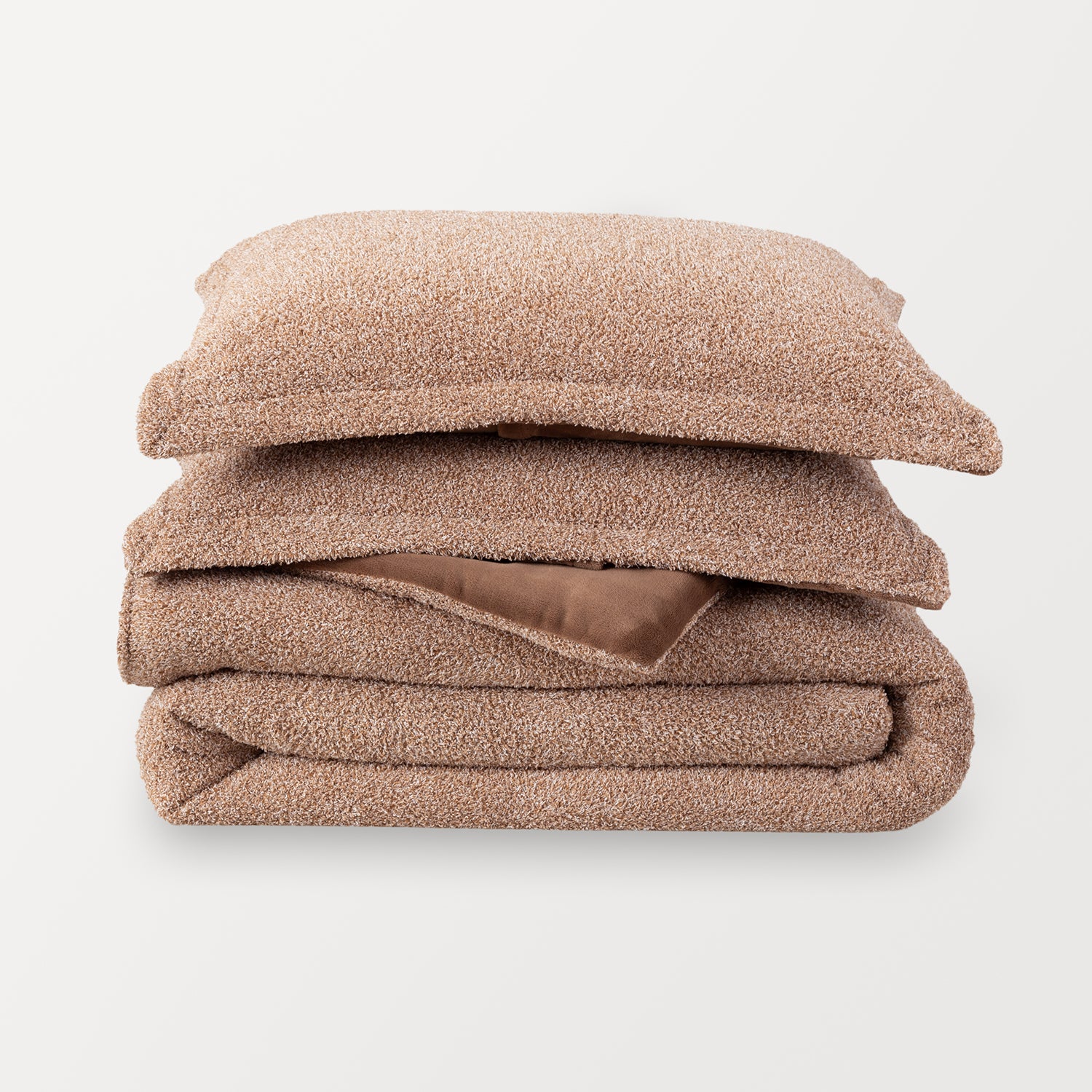A single retro plush comforter folded and stacked with two matching pillow shams stacked in a pile. Sumatra Blend color is a medium brown color mixed with white specs.