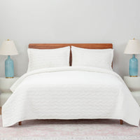 A bed made with the White VelvetLoft® Quilt Set, showcasing a clean and crisp bedding arrangement.