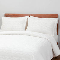 A bed made with the White VelvetLoft® Quilt Set, showcasing a clean and crisp bedding arrangement.