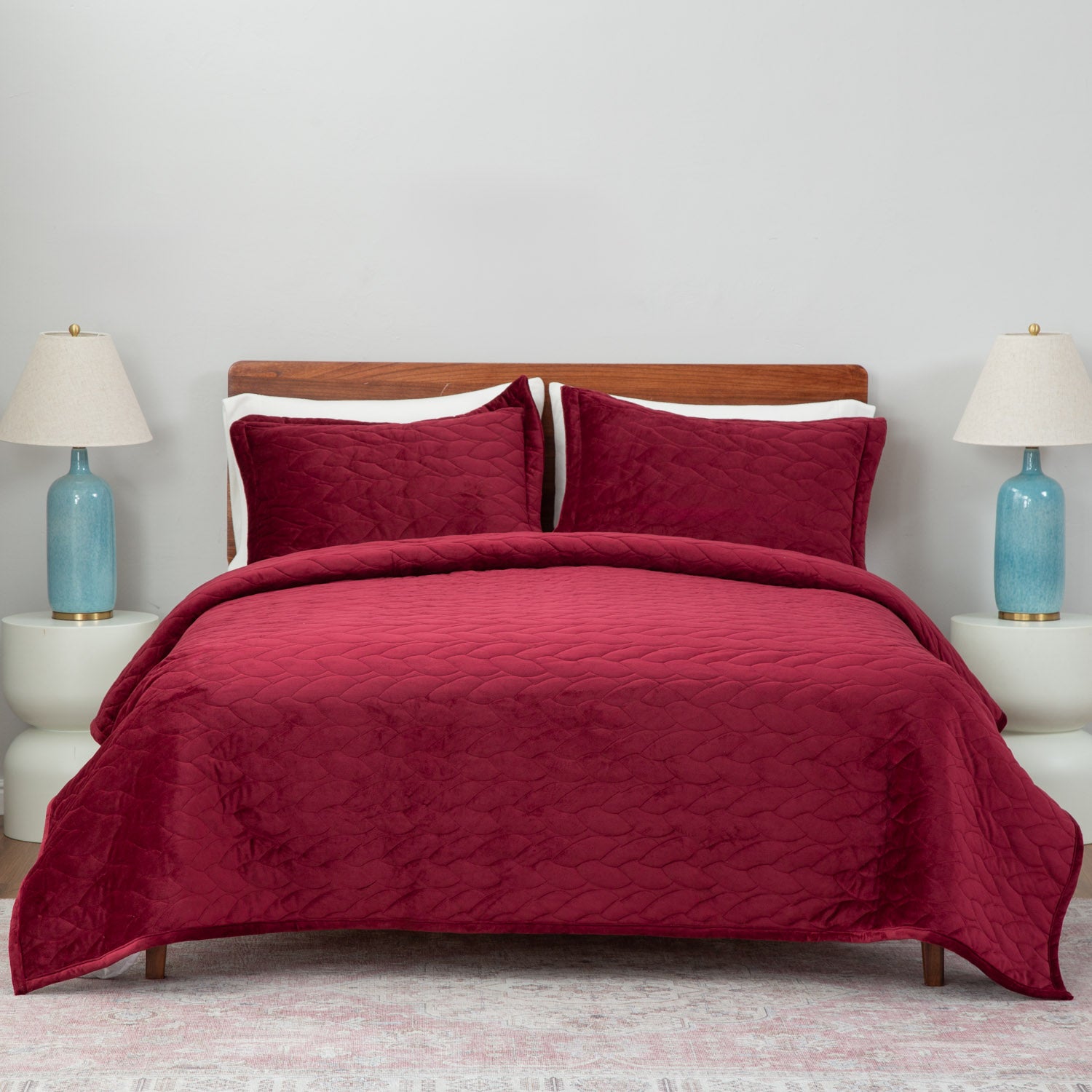 Red quilt set decorated on a bed in a neutral bedroom.