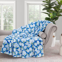 Krissy Mast Artist Series printed hydrangea print throw draped neatly over a grey sofa in a staged room.