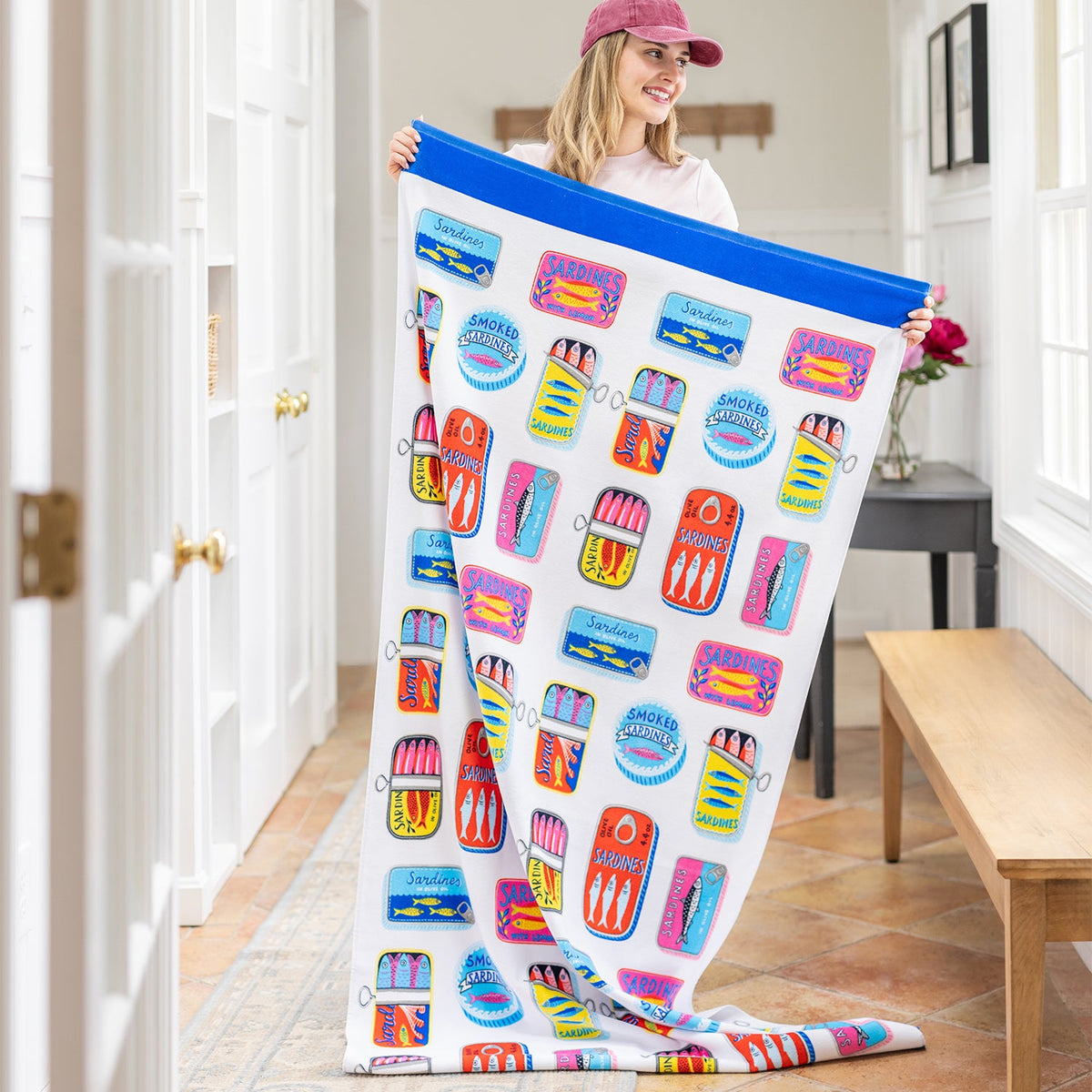 Image of a girl holding up an oversized beach towel with a fun sardine print