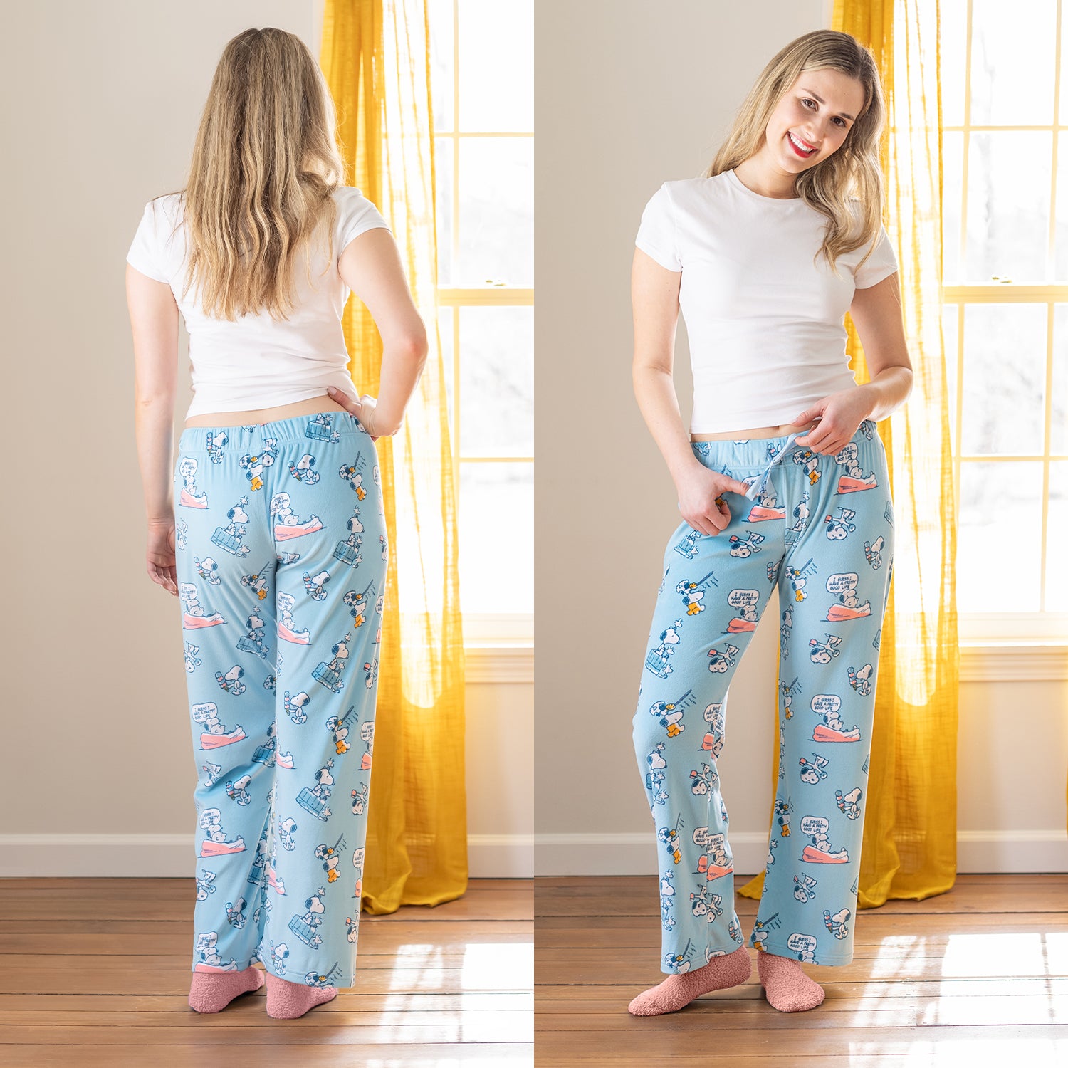 A woman wearing blue Peanuts printed lounge pants while tanding in a living room.