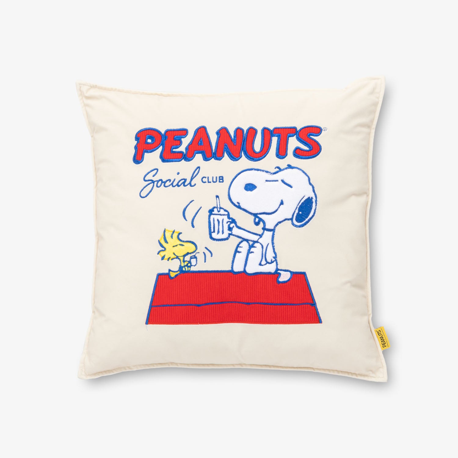 Peanuts Social Club Pillow sitting on a white surface.