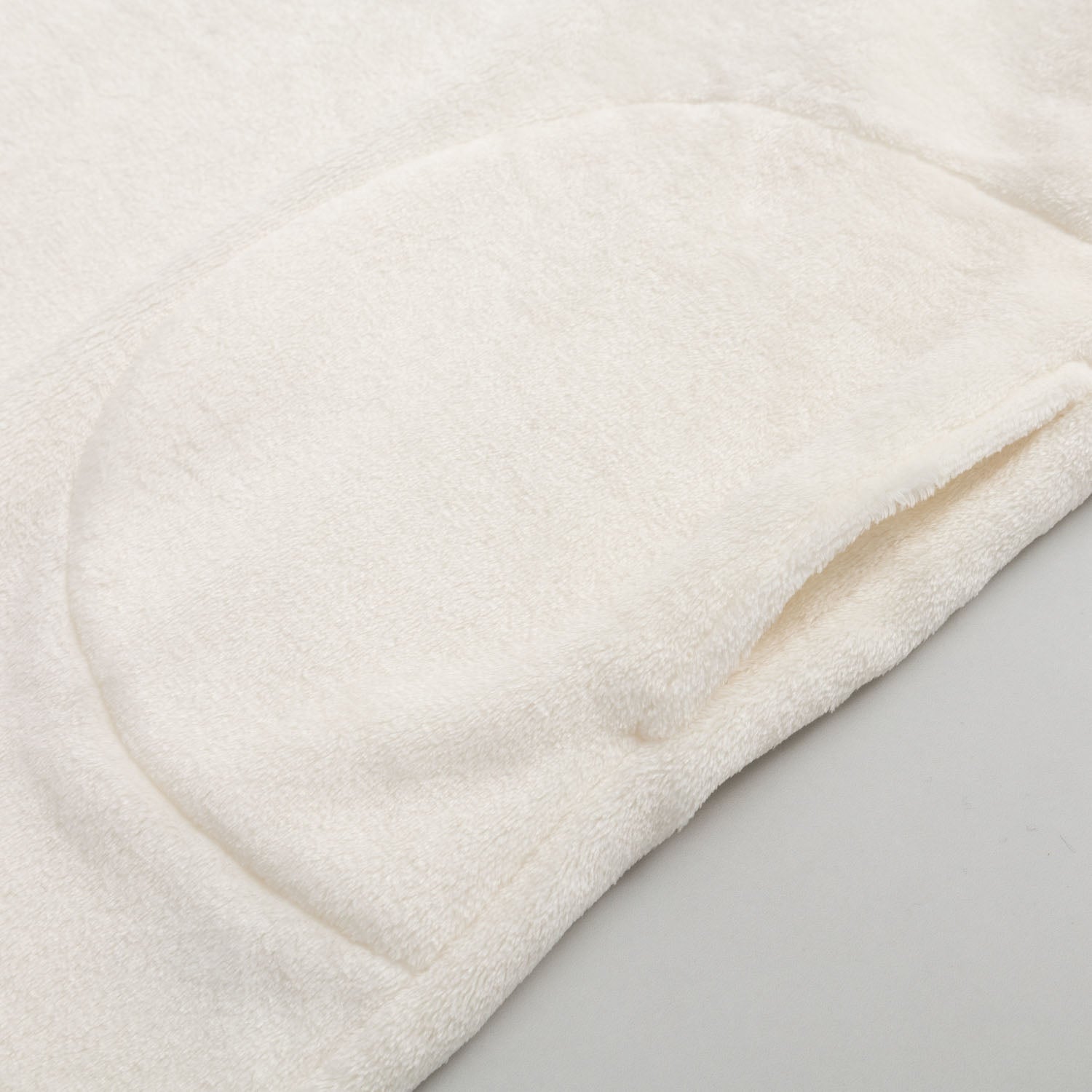 Close up of the pocket of our Peanuts social club embroidered lounge hoodie on a white surface.