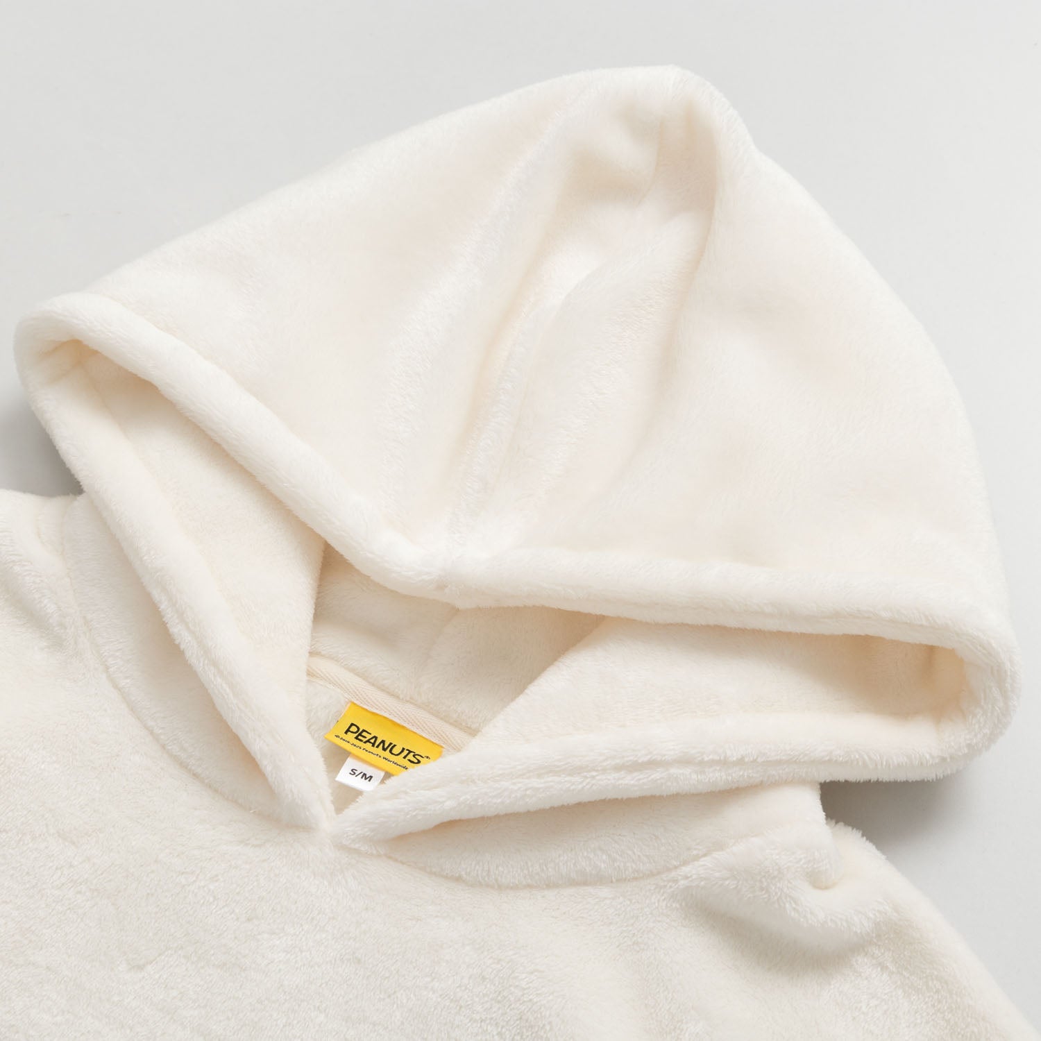 Close up of the hood on our Peanuts social club embroidered lounge hoodie hung laying on a white surface.