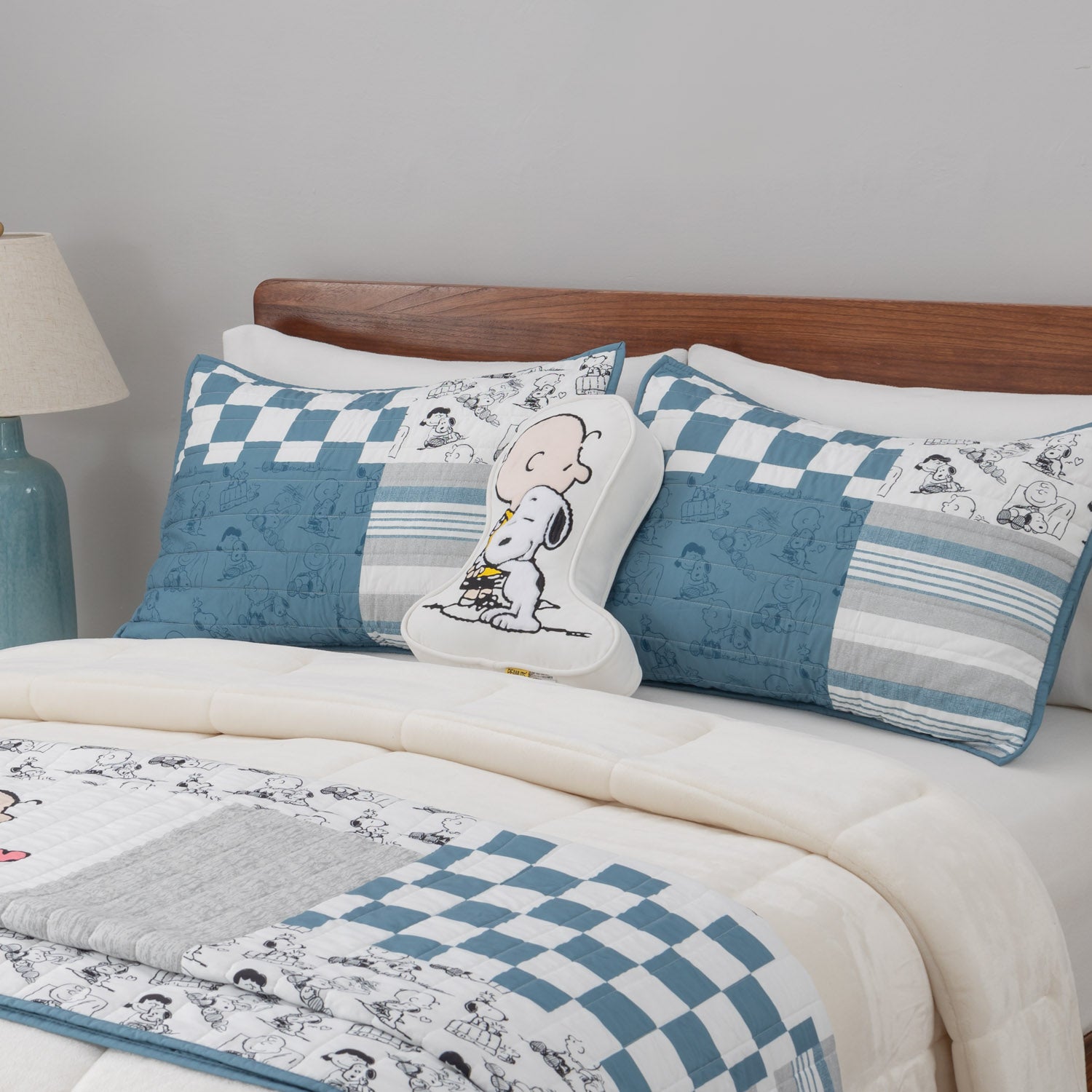 Peanuts patchwork quilt set dressed on a bed with a peanuts pillow.
