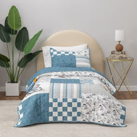 Patchwork quilt set on a bed with a side table and plant in the background
