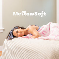 Woman lying on a couch with a pink blanket, featuring the 'MellowSoft' fabric name.