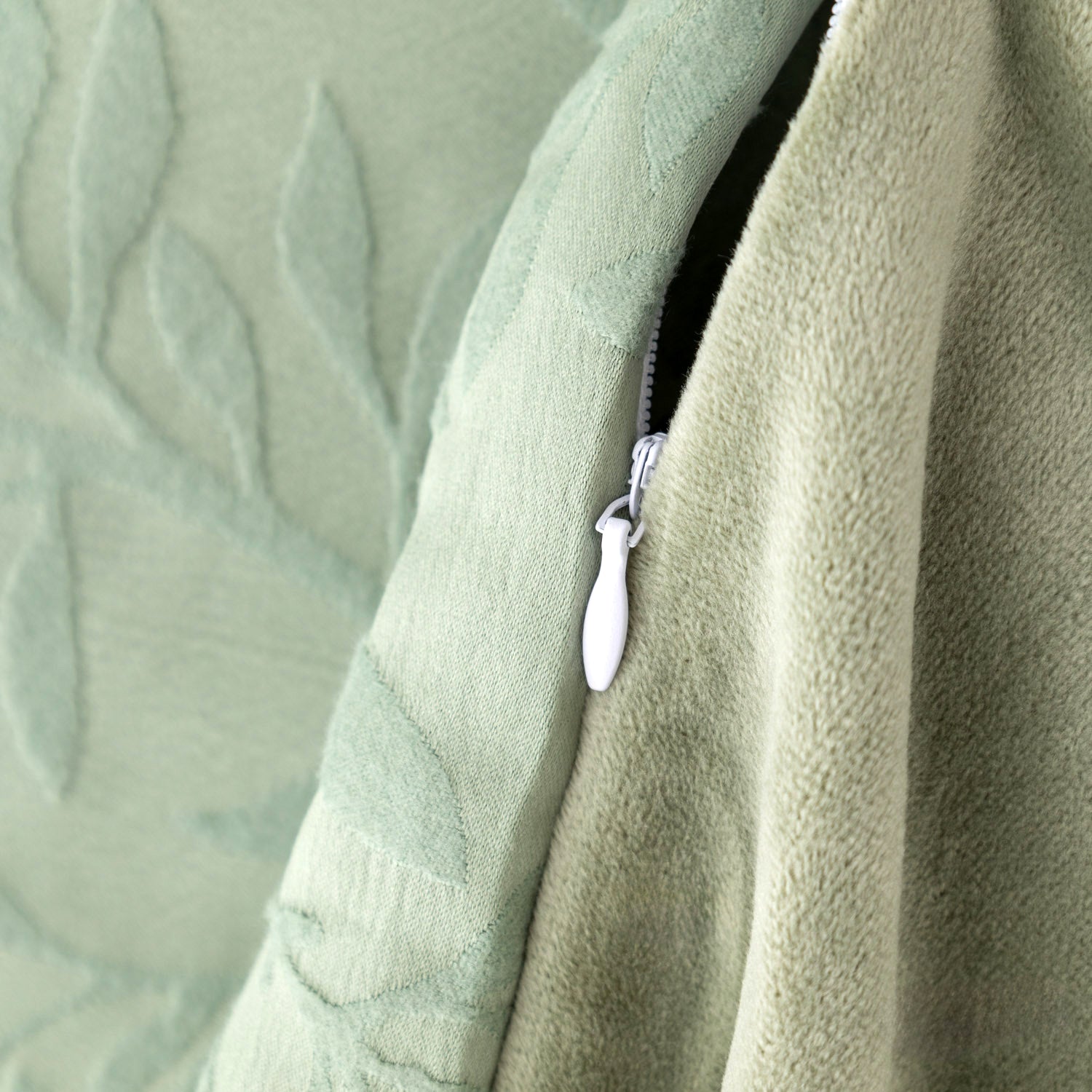 Close-up of a green textured fabric with a zipper detail