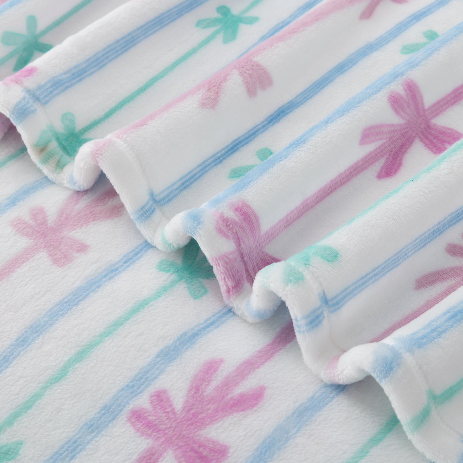 Close-up of a soft fabric with pink and blue  and green bow patterns on a white blanket