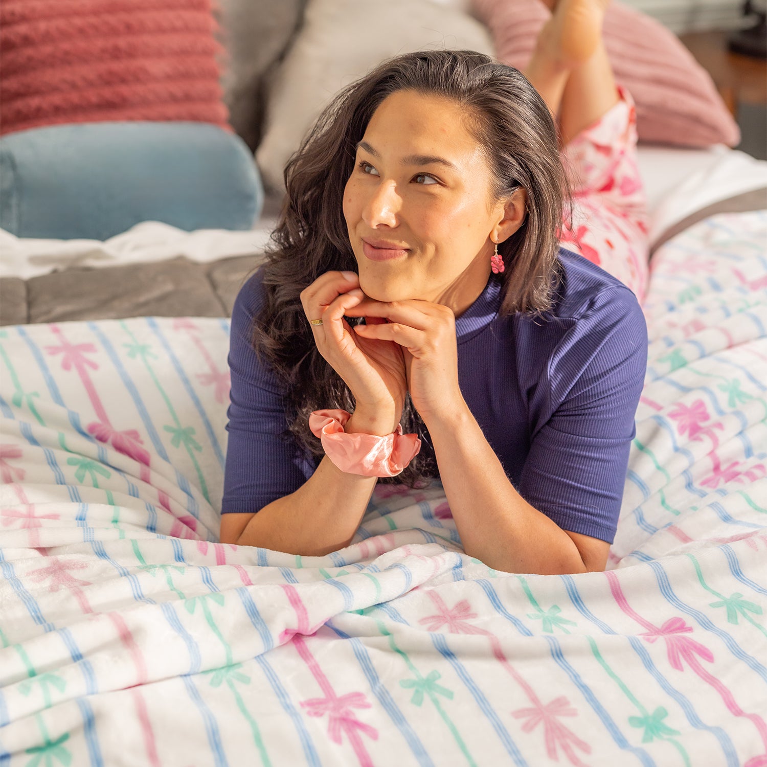Woman lying on a bed with colorful striped blanket