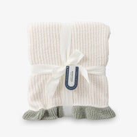 Knitted blanket with a white ribbon and tag on a white background