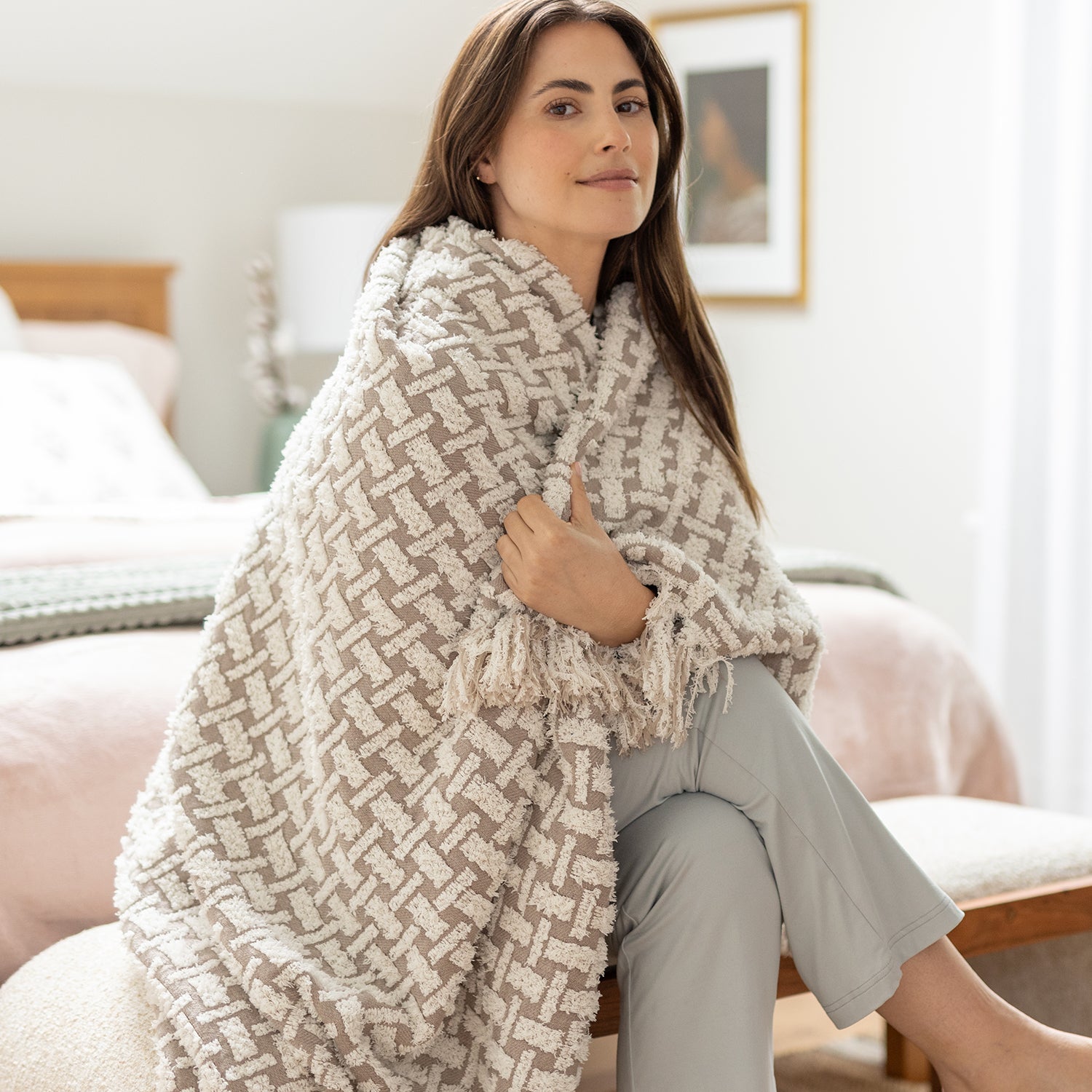 Woman wrapped in a patterned blanket sitting on a couch in a cozy living room.